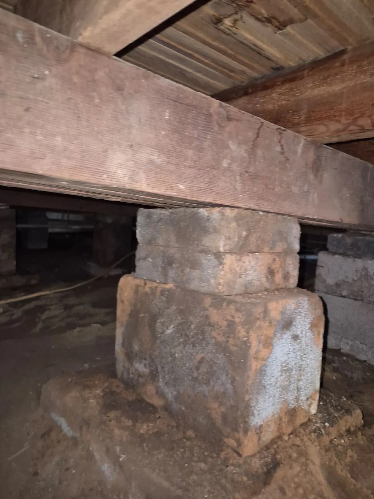 Stacked concrete blocks supporting a wood beam in a crawl space under a pier and beam house